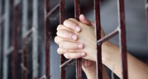 hands behind prison bars