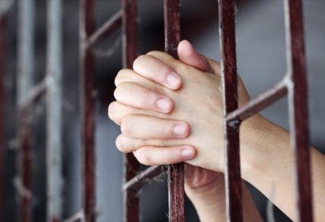 hands behind prison bars