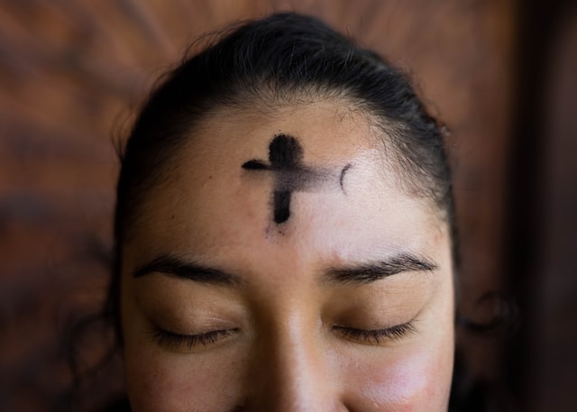 black cross in ash on person's forehead