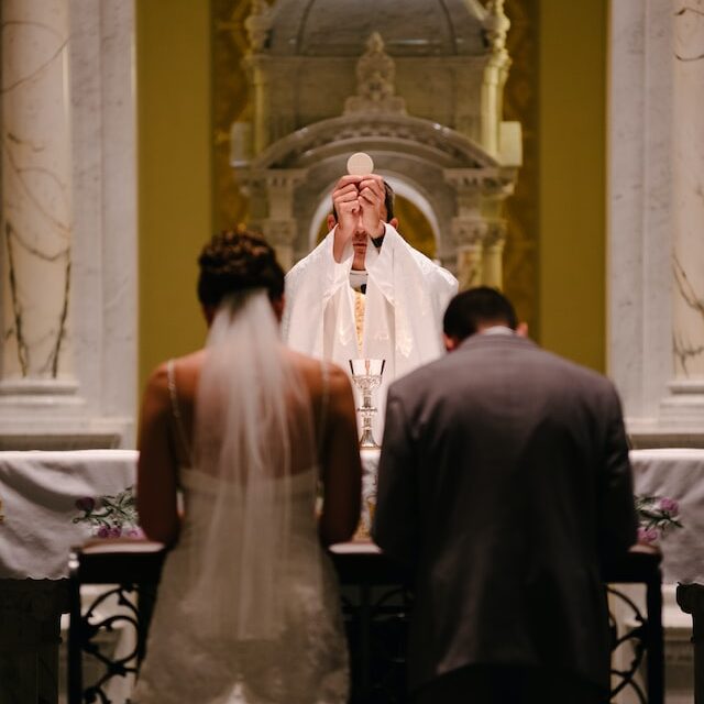 Couple kneels before the altar during wedding