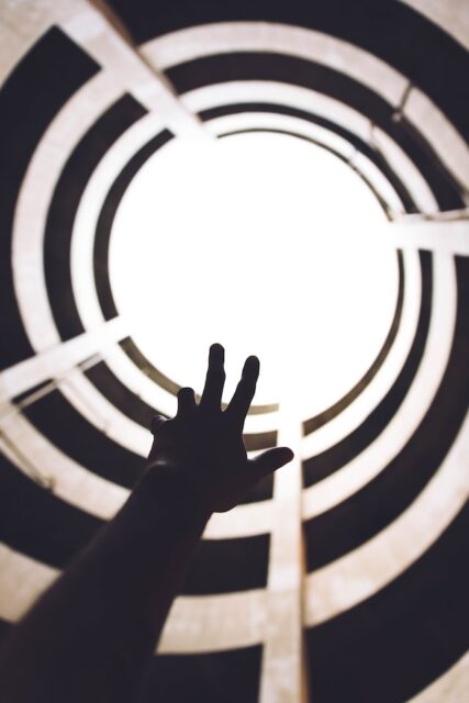 Hand reaching for the sunlight from inside a building
