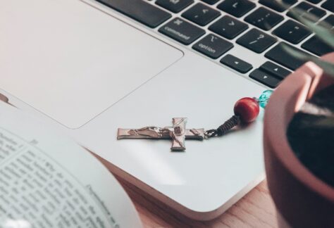 rosary and bible near open laptop