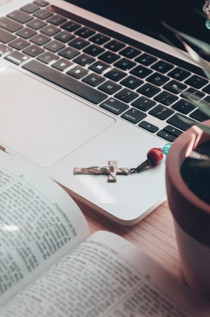 rosary and bible near open laptop