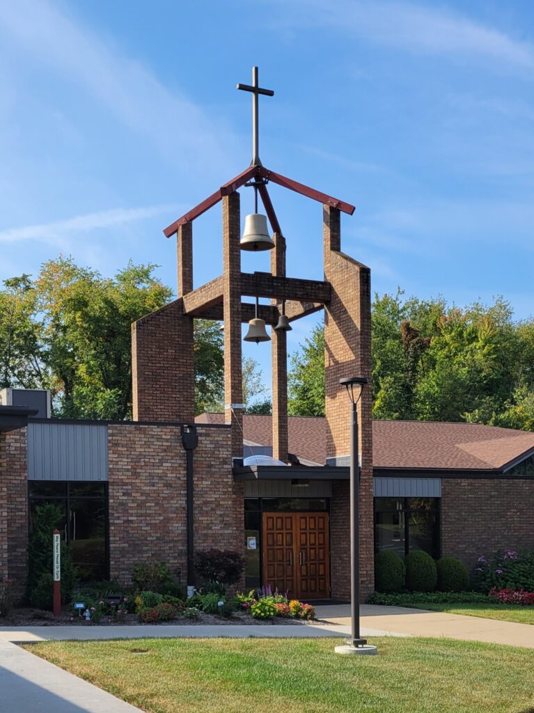 Front door of Holy Spirit Parish in Uniontown, Ohio with bells and cross above