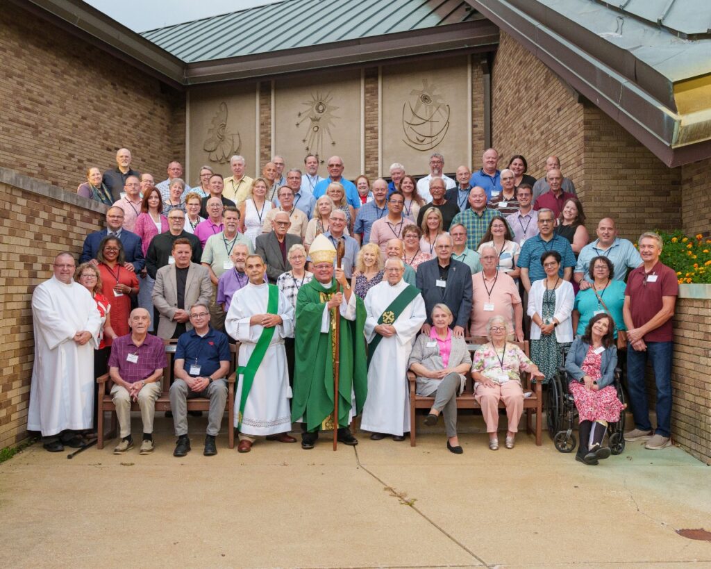 Deacons and their wives from the Diocese of Youngstown surround Bishop David Bonnar on the steps in front of the chapel at Villa Maria