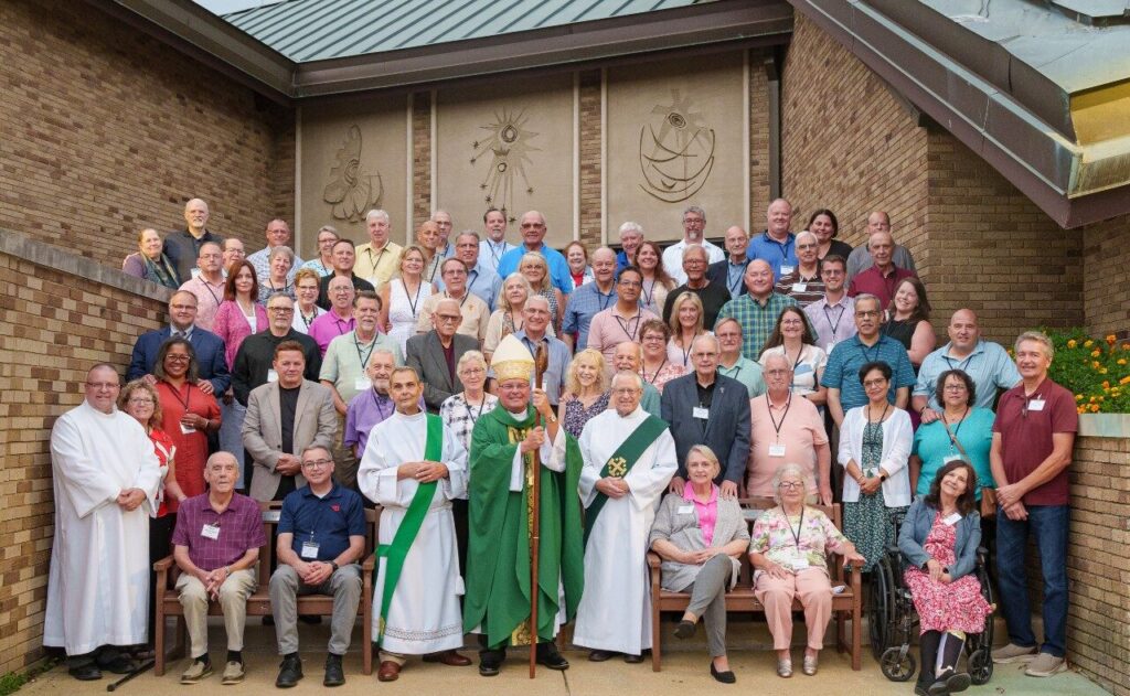 Deacons and their wives from the Diocese of Youngstown surround Bishop David Bonnar on the steps in front of the chapel at Villa Maria