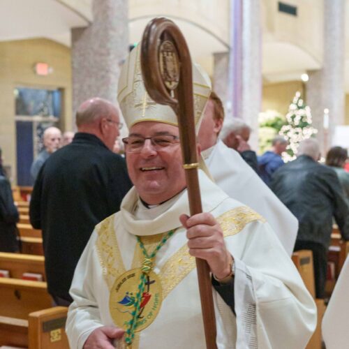 Bishop Bonnar holds his staff and wears white vestments with gold trim and the Jubilee 2025 logo that reads "Pilgrims of Hope."