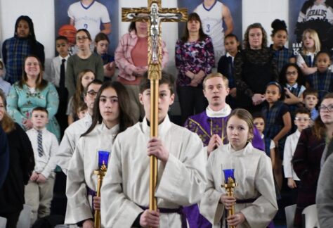 Servers wearing white and carrying cross and purple candles for Ash Wednesday