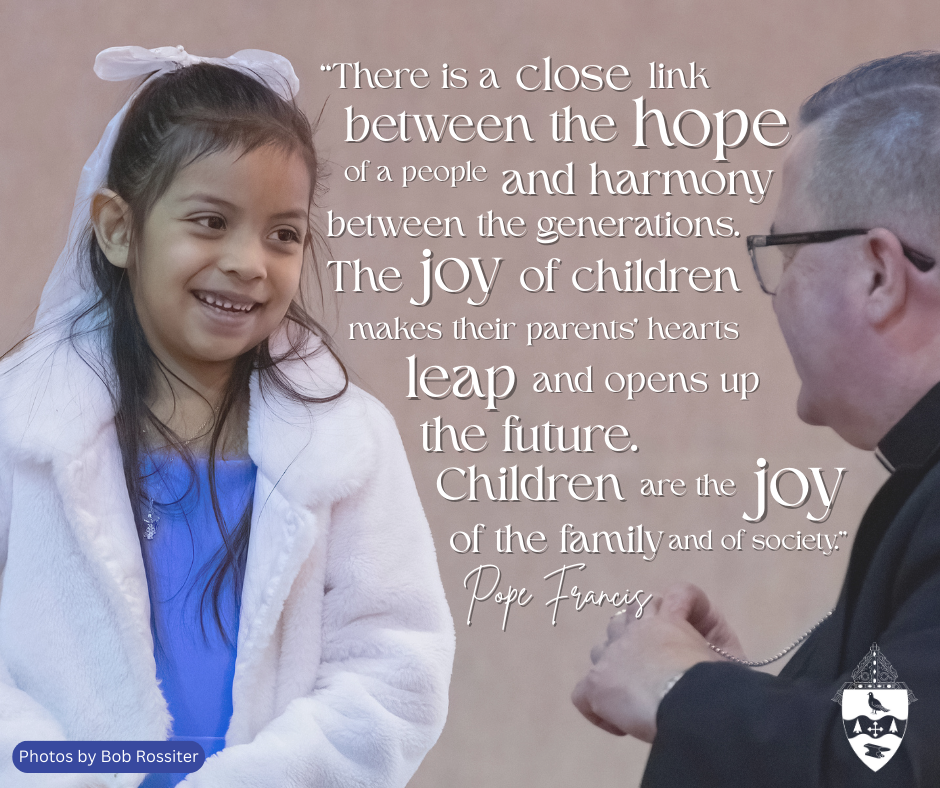 Bishop David Bonnar speaks to a smiling young girl.